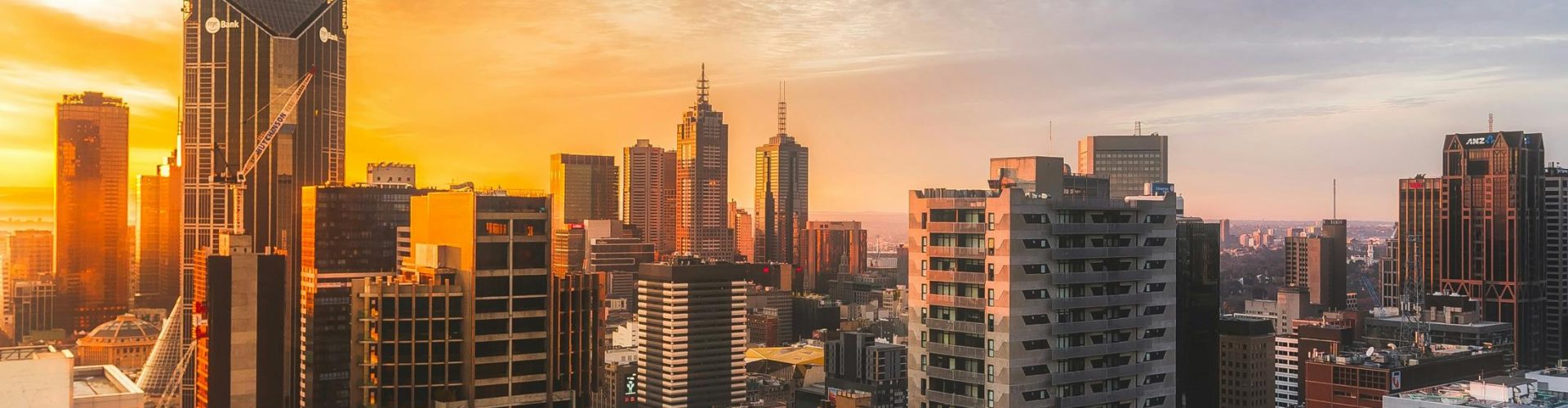 Stunning view of Melbourne's skyline at sunset, capturing modern skyscrapers and warm sky.